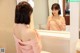 A woman standing in front of a mirror in a bathroom.