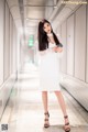 A woman in a white dress standing in a hallway.