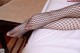 A woman in fishnet stockings laying on a bed.