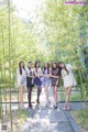 A group of young women standing next to each other in a bamboo forest.