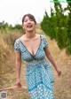 A woman in a blue dress walking down a dirt road.