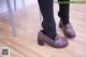 A woman wearing black tights and brown shoes standing on a wooden floor.