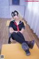 A woman in a school uniform sitting on a desk.