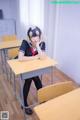 A woman sitting at a desk in a classroom.