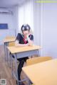 A woman sitting at a desk in a classroom.