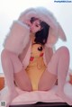 A woman in a yellow bodysuit sitting on a bed.