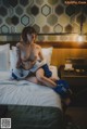 A naked woman sitting on a bed in a hotel room.