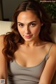 A woman in a gray tank top sitting on a couch.
