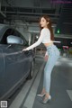 A woman standing next to a car in a parking garage.