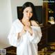 A woman in a white robe standing in a hotel room.