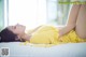 A woman in a yellow dress laying on a bed.