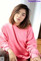 A woman in a pink sweatshirt sitting on a couch.