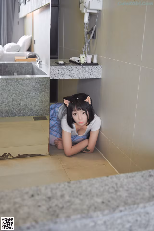 A woman laying on the floor in a bathroom.