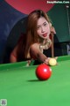 A woman in a red bikini playing pool.