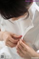 A woman in a white shirt is putting on her tie.