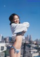 A woman in a bikini standing on top of a roof.