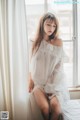 A woman in a white dress sitting on a window sill.