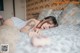 A woman laying on a bed with a teddy bear.