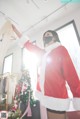 A woman in a santa suit holding up a piece of clothing.