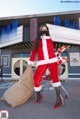 A woman dressed as Santa Claus pushing a shopping cart.