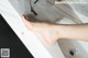 A woman's feet in a bathroom sink with a red nail polish.