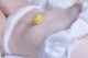 A woman laying on a bed with a yellow macaron on her stomach.