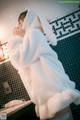 A woman in a white bunny robe standing in a bathroom.