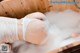 A woman in a white bikini is taking a bath in a wooden tub.