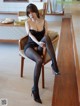 A woman sitting on a chair wearing black stockings and high heels.