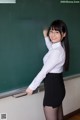 A woman standing in front of a blackboard writing on it.