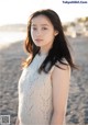 A woman in a white sweater standing on a beach.