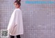 A woman standing in front of a brick wall.