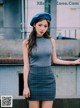 A woman wearing a blue beret standing on a ledge.