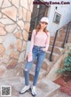 a woman standing on the steps of a building wearing a pink shirt and jeans