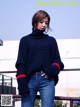 a woman wearing a black sweater and jeans standing on a railing