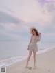 A woman standing on a beach next to the ocean.