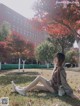 A woman sitting on the ground in front of a tree.