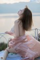 A woman in a pink dress sitting on a balcony.