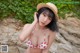 A woman in a bikini and a straw hat posing for a picture.