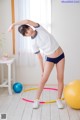 A woman in a white shirt and blue shorts is doing a yoga pose.