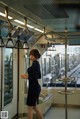 A woman in a black dress standing on a subway train.