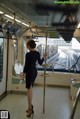 A woman in a black dress standing on a subway train.