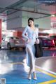 A woman in a blue dress standing in a parking garage.