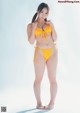 A woman in a yellow bikini posing for a picture.