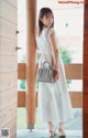 A woman in a white dress standing on a porch.