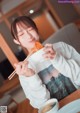 A woman eating a bowl of food with chopsticks.