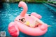 A woman in a yellow bikini laying on an inflatable flamingo.