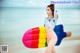 A woman in a bikini holding an inflatable popsicle on the beach.