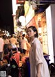 A woman standing in the middle of a busy street at night.