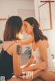 A couple of women sitting on top of a bed.